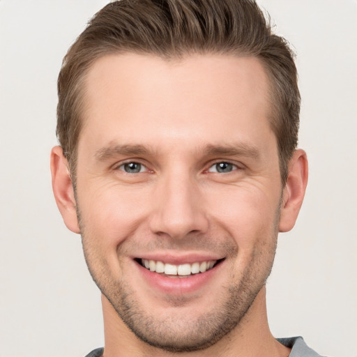 Joyful white young-adult male with short  brown hair and grey eyes