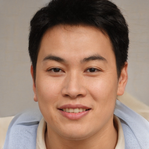Joyful asian young-adult male with short  brown hair and brown eyes
