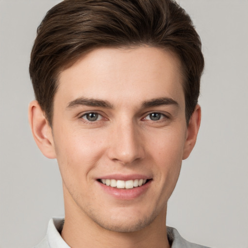 Joyful white young-adult male with short  brown hair and grey eyes