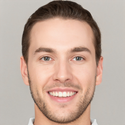 Joyful white young-adult male with short  brown hair and grey eyes