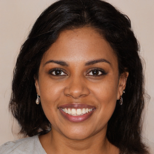 Joyful black young-adult female with long  brown hair and brown eyes