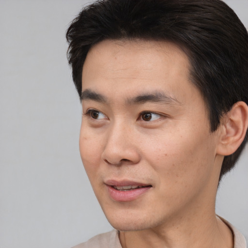 Joyful asian young-adult male with short  black hair and brown eyes