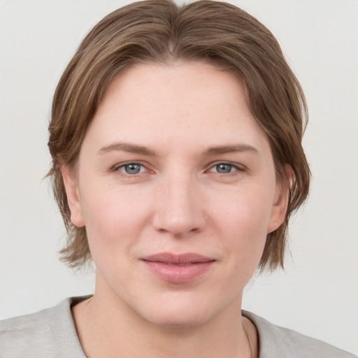 Joyful white young-adult female with medium  brown hair and grey eyes