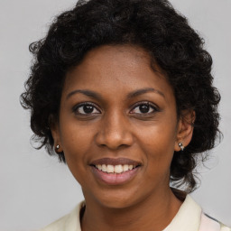 Joyful black young-adult female with long  brown hair and brown eyes