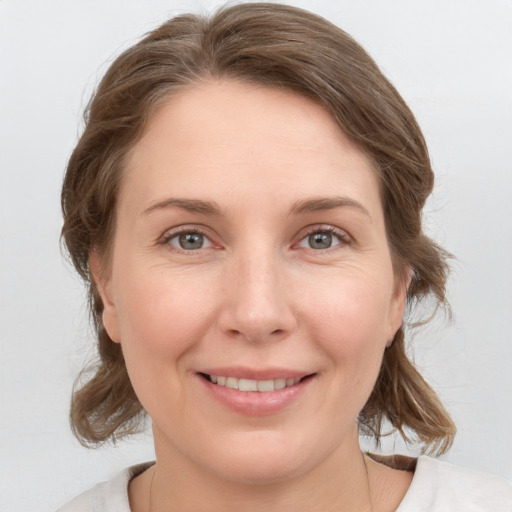 Joyful white young-adult female with medium  brown hair and grey eyes