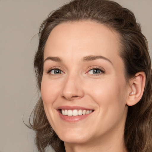 Joyful white young-adult female with medium  brown hair and grey eyes