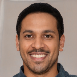 Joyful latino young-adult male with short  black hair and brown eyes