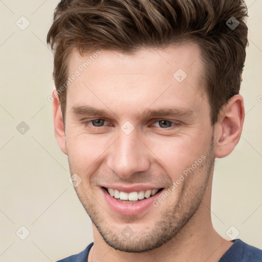 Joyful white young-adult male with short  brown hair and grey eyes