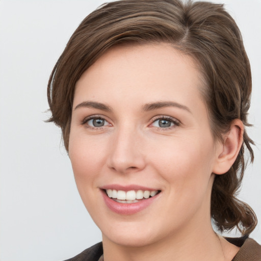 Joyful white young-adult female with medium  brown hair and grey eyes