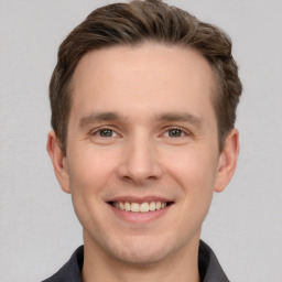 Joyful white young-adult male with short  brown hair and grey eyes