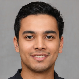 Joyful latino young-adult male with short  black hair and brown eyes