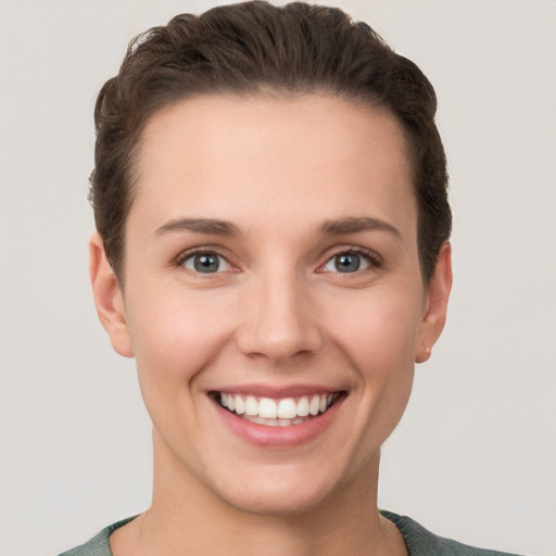 Joyful white young-adult female with short  brown hair and grey eyes