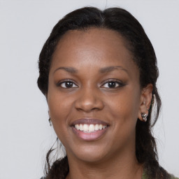 Joyful black young-adult female with long  brown hair and brown eyes