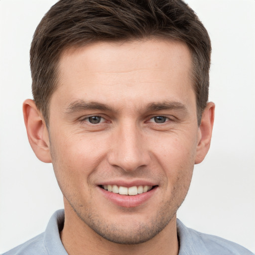 Joyful white young-adult male with short  brown hair and grey eyes