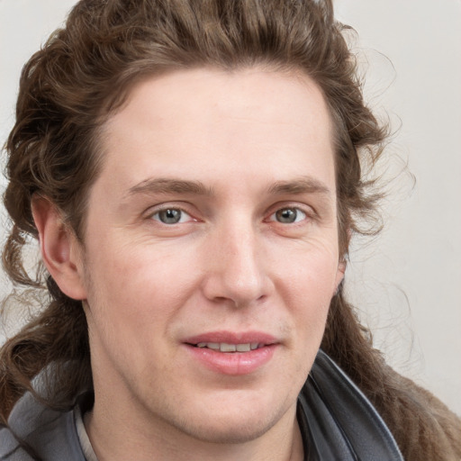 Joyful white young-adult male with long  brown hair and blue eyes