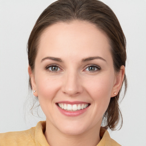 Joyful white young-adult female with medium  brown hair and grey eyes