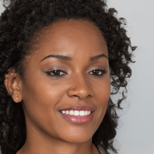 Joyful black young-adult female with long  brown hair and brown eyes