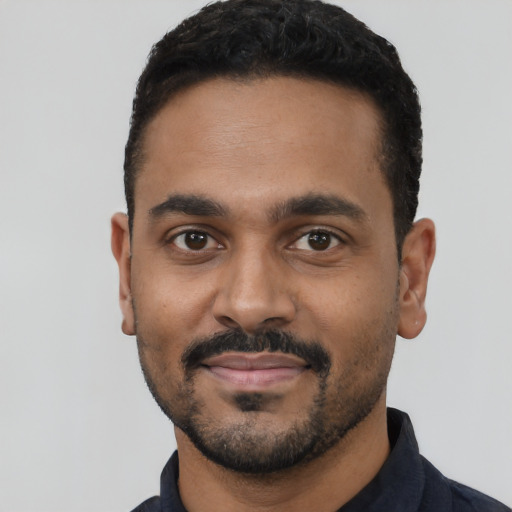 Joyful black young-adult male with short  black hair and brown eyes