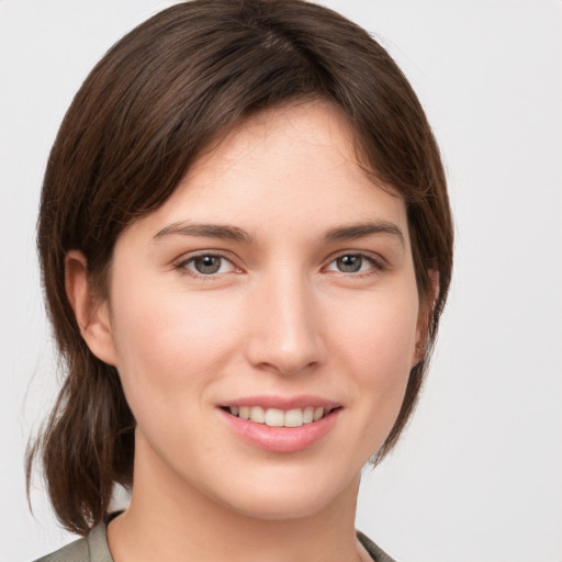 Joyful white young-adult female with medium  brown hair and grey eyes