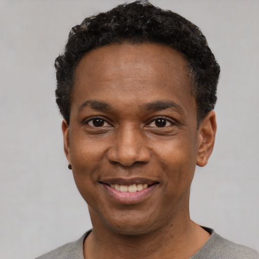 Joyful black young-adult male with short  black hair and brown eyes