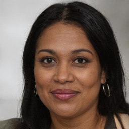 Joyful black adult female with long  brown hair and brown eyes