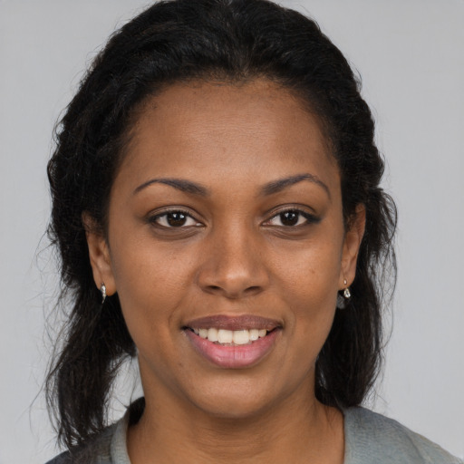 Joyful black young-adult female with long  brown hair and brown eyes