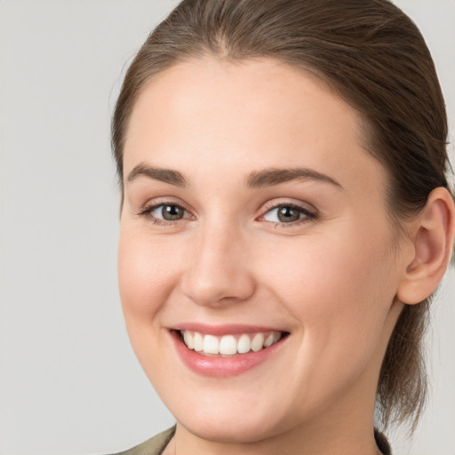 Joyful white young-adult female with medium  brown hair and grey eyes