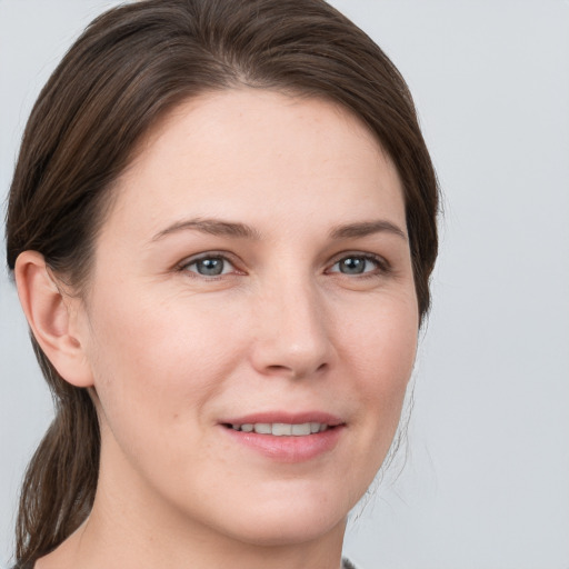 Joyful white young-adult female with medium  brown hair and grey eyes