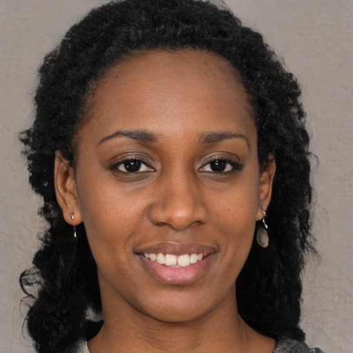 Joyful black young-adult female with long  brown hair and brown eyes