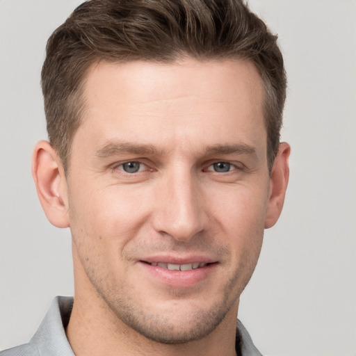 Joyful white young-adult male with short  brown hair and grey eyes