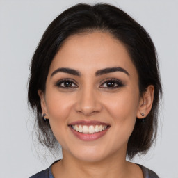 Joyful latino young-adult female with medium  brown hair and brown eyes