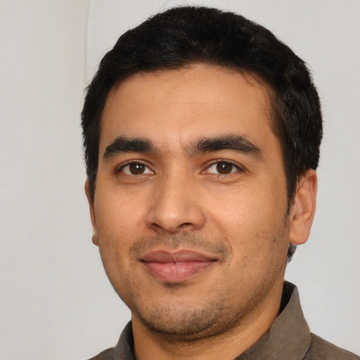Joyful latino young-adult male with short  black hair and brown eyes