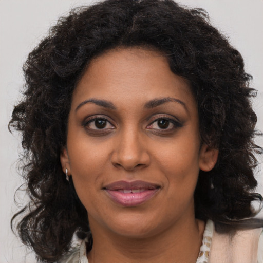 Joyful black young-adult female with long  brown hair and brown eyes