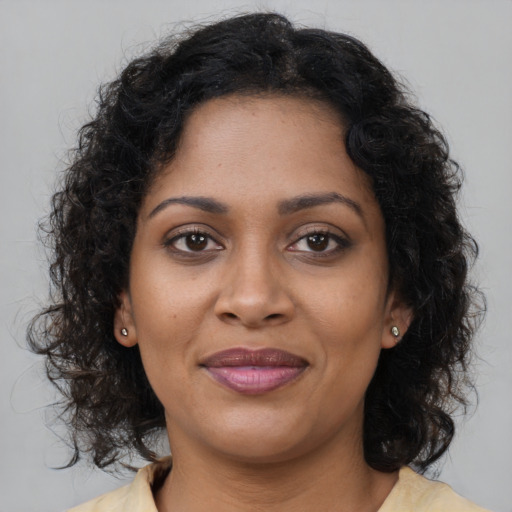 Joyful black young-adult female with long  brown hair and brown eyes