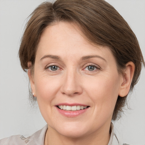 Joyful white adult female with medium  brown hair and grey eyes