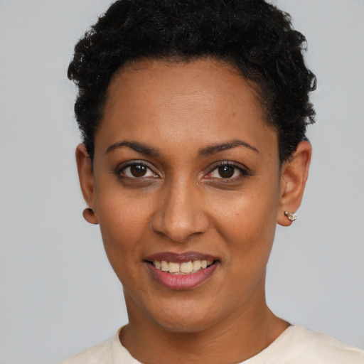 Joyful black young-adult female with short  black hair and brown eyes