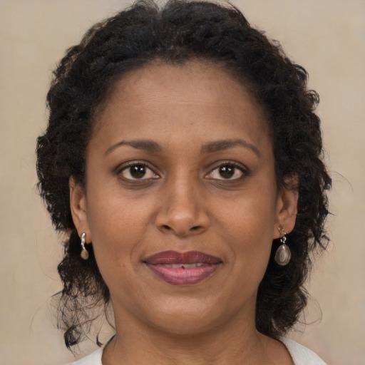 Joyful black adult female with long  brown hair and brown eyes