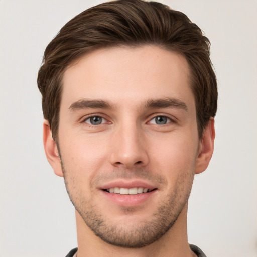 Joyful white young-adult male with short  brown hair and grey eyes