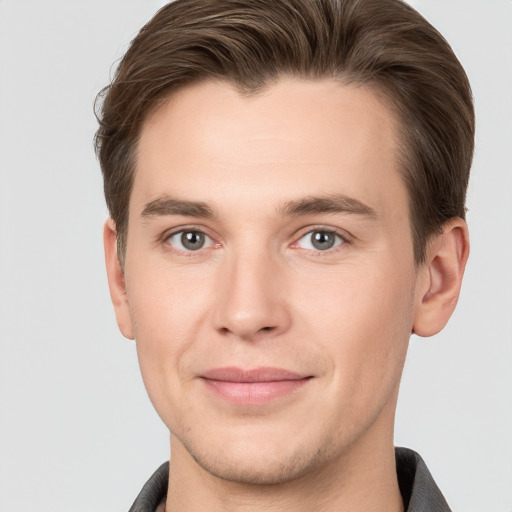 Joyful white young-adult male with short  brown hair and grey eyes