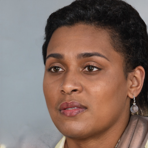 Joyful black young-adult female with short  black hair and brown eyes