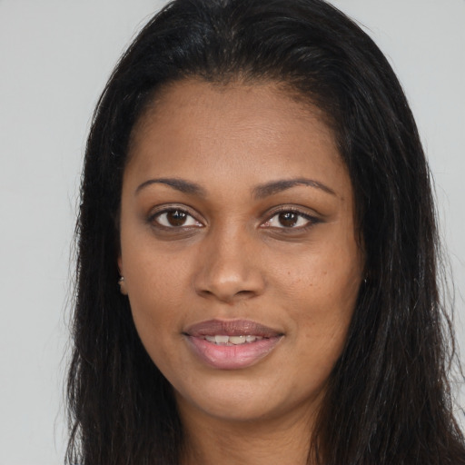 Joyful black young-adult female with long  brown hair and brown eyes
