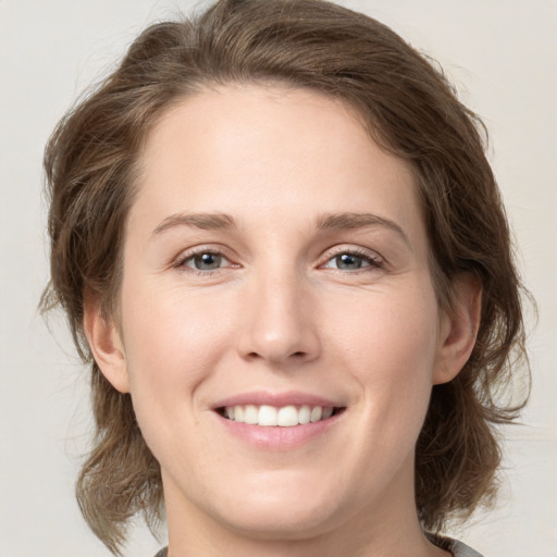 Joyful white young-adult female with medium  brown hair and grey eyes