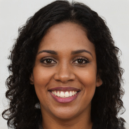 Joyful black young-adult female with long  brown hair and brown eyes