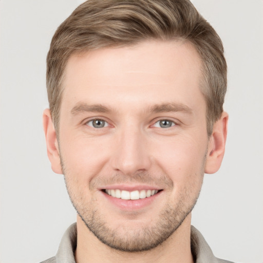 Joyful white young-adult male with short  brown hair and grey eyes