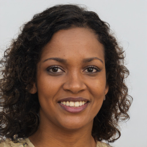 Joyful black young-adult female with long  brown hair and brown eyes