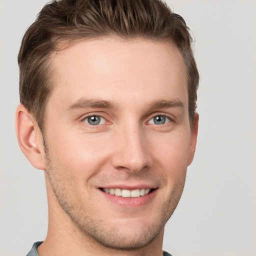 Joyful white young-adult male with short  brown hair and grey eyes