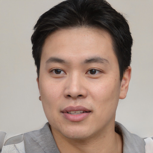 Joyful asian young-adult male with short  black hair and brown eyes