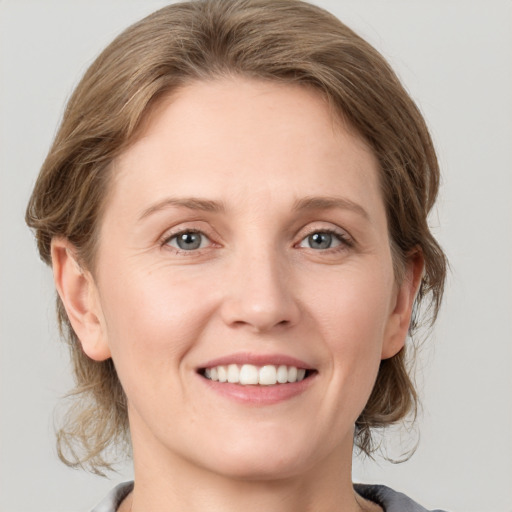 Joyful white young-adult female with medium  brown hair and grey eyes