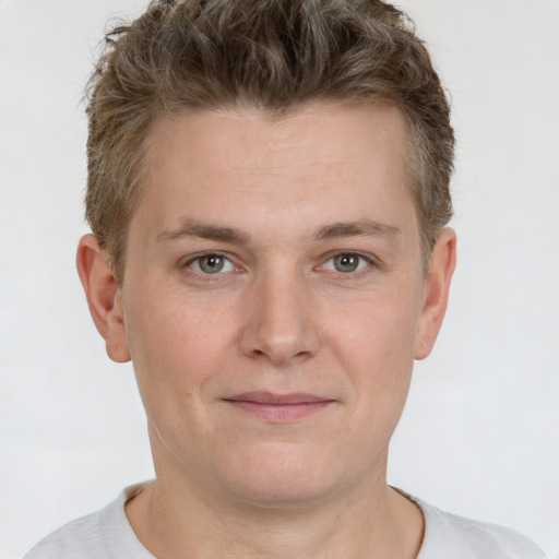 Joyful white young-adult male with short  brown hair and grey eyes