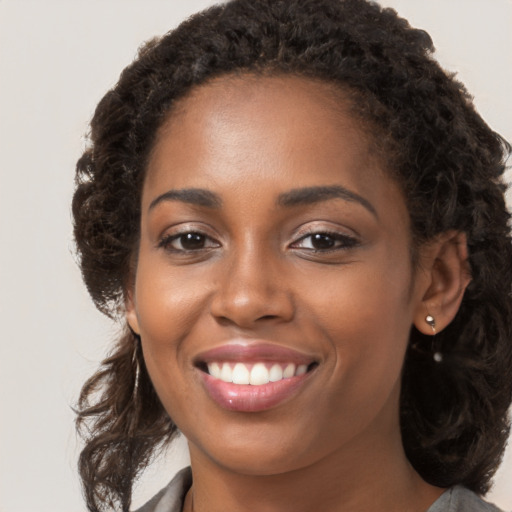 Joyful black young-adult female with long  brown hair and brown eyes